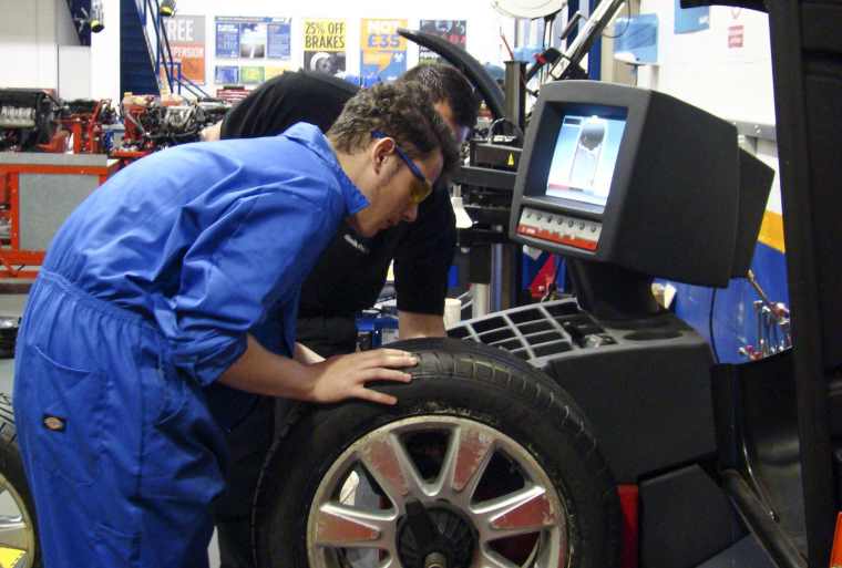 Apprentice using wheel balancing machine