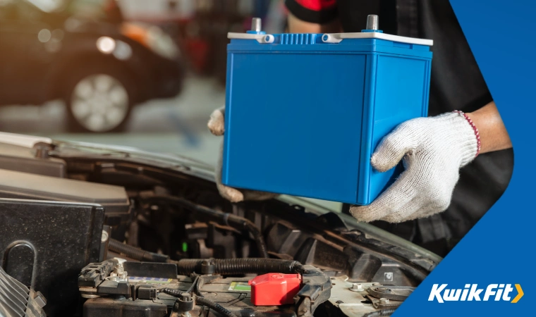 Technician with white gloves fitting a battery into a car.