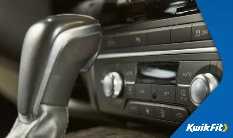 A close up of the gear stick and radio area in an automatic car.