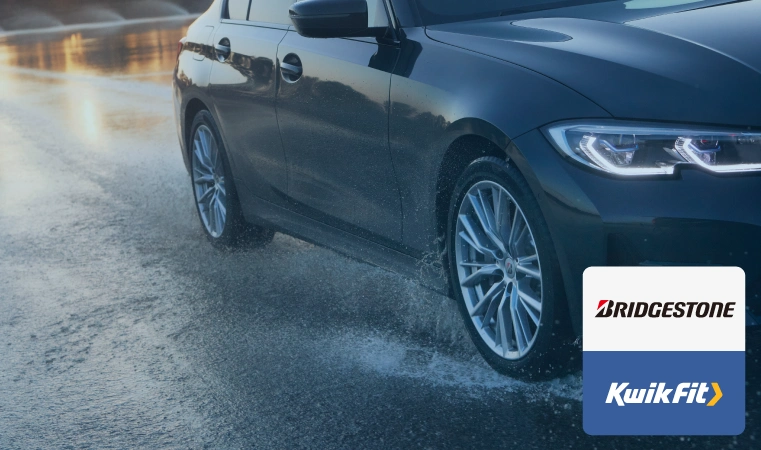 Vehicle with Bridgestone tyres driving on a wet road.