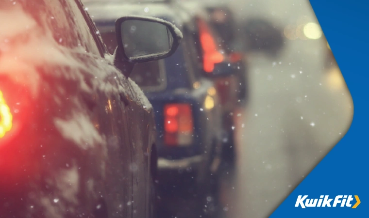 A view of motorway traffic in the snow, with headlights and brake lights out of focus.