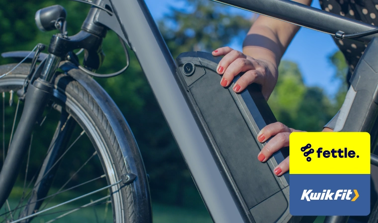 A pair of hands with orange nail varnish checking the battery of an electric bike.