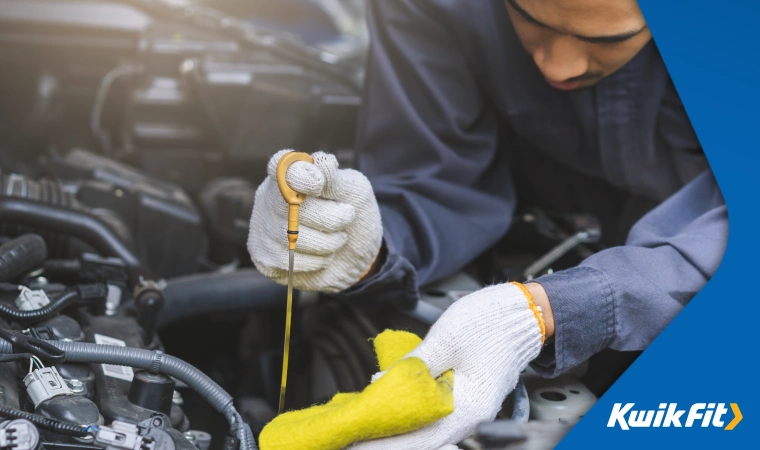 Technician testing oil levels underneath the bonnet of a car.