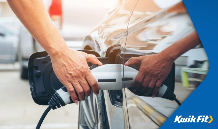 Person plugging in an EV charger into an Electric vehicle.