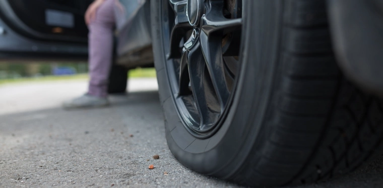 Person sitting out their vehicle with the door open after getting a flat tyre