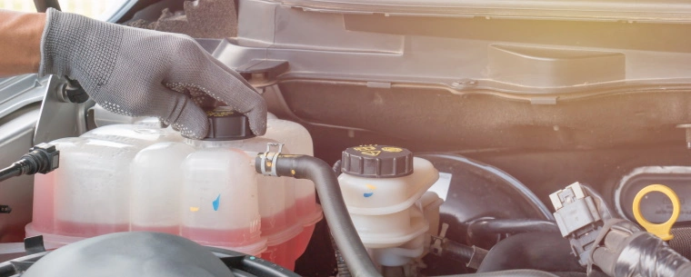 Car bonnet opened with person adjusting engine coolant cap