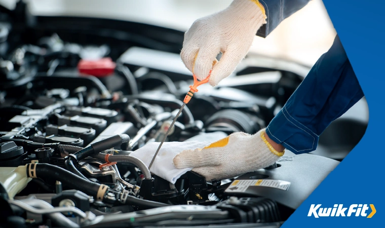 Technician pulling out oil dipstick and wiping it with a cloth.