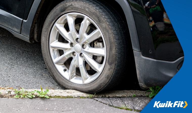 Car wheel parked up over the pavement.