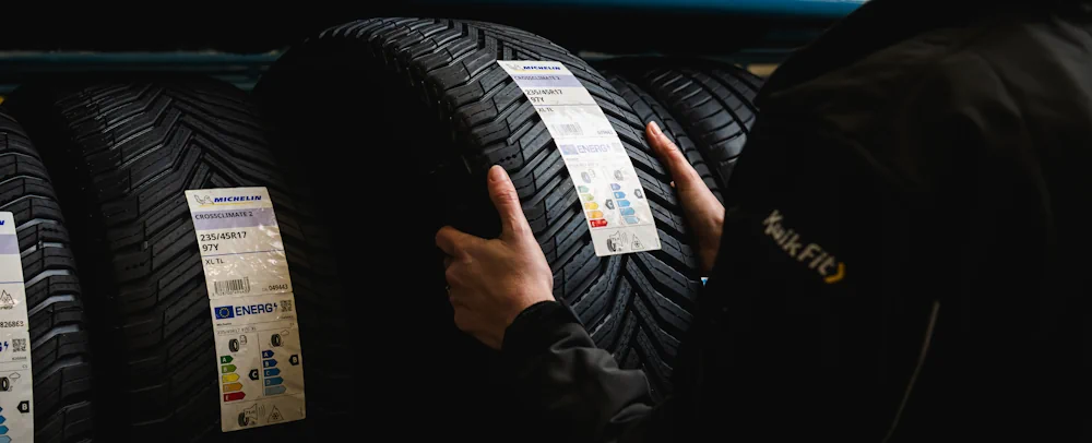 Kwik Fit technician pulling out tyre from a rack of tyres