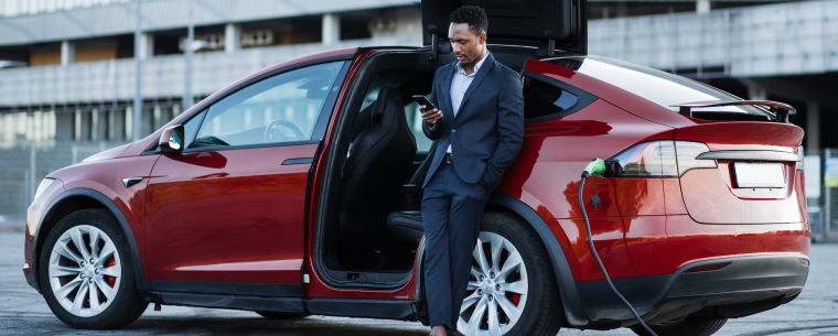 Man leaning against a car while it charges