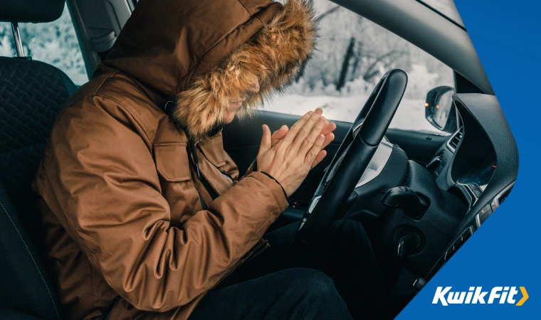 Person in car attempting to warm up with broken heating.