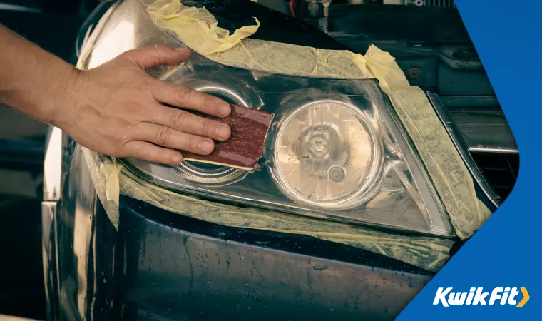 Someone polishing plastic headlight covers with fine grit sandpaper in order to make them clear again.