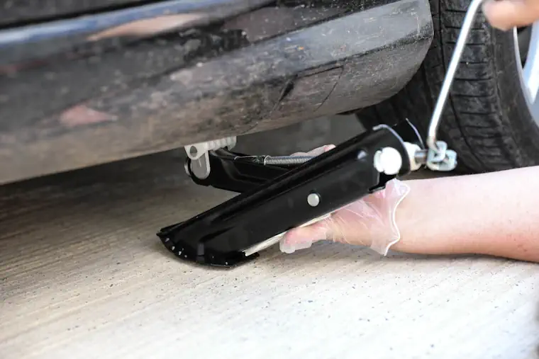 Person finding the jacking point on a car.