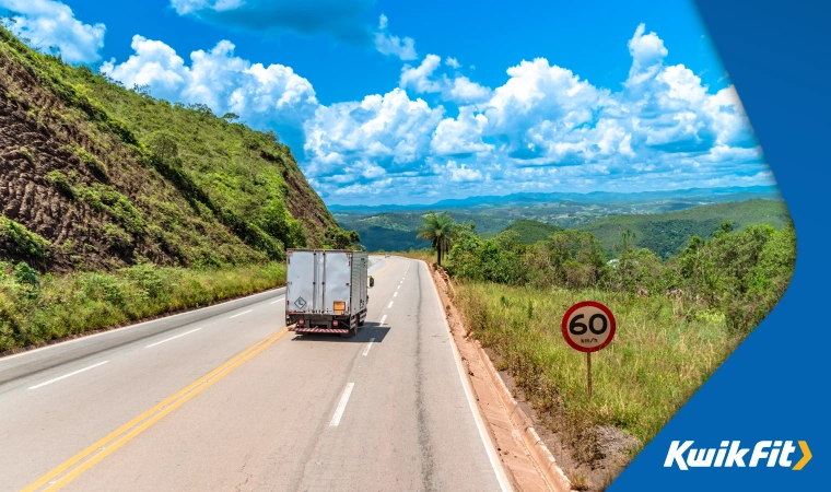 A lush green landscape in South America with a van driving on the right side of the road.