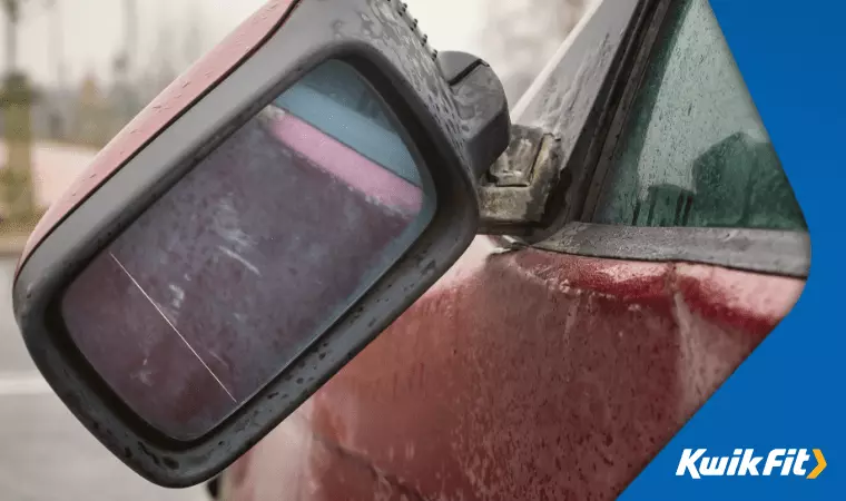 A broken wing mirror hanging off in the rain